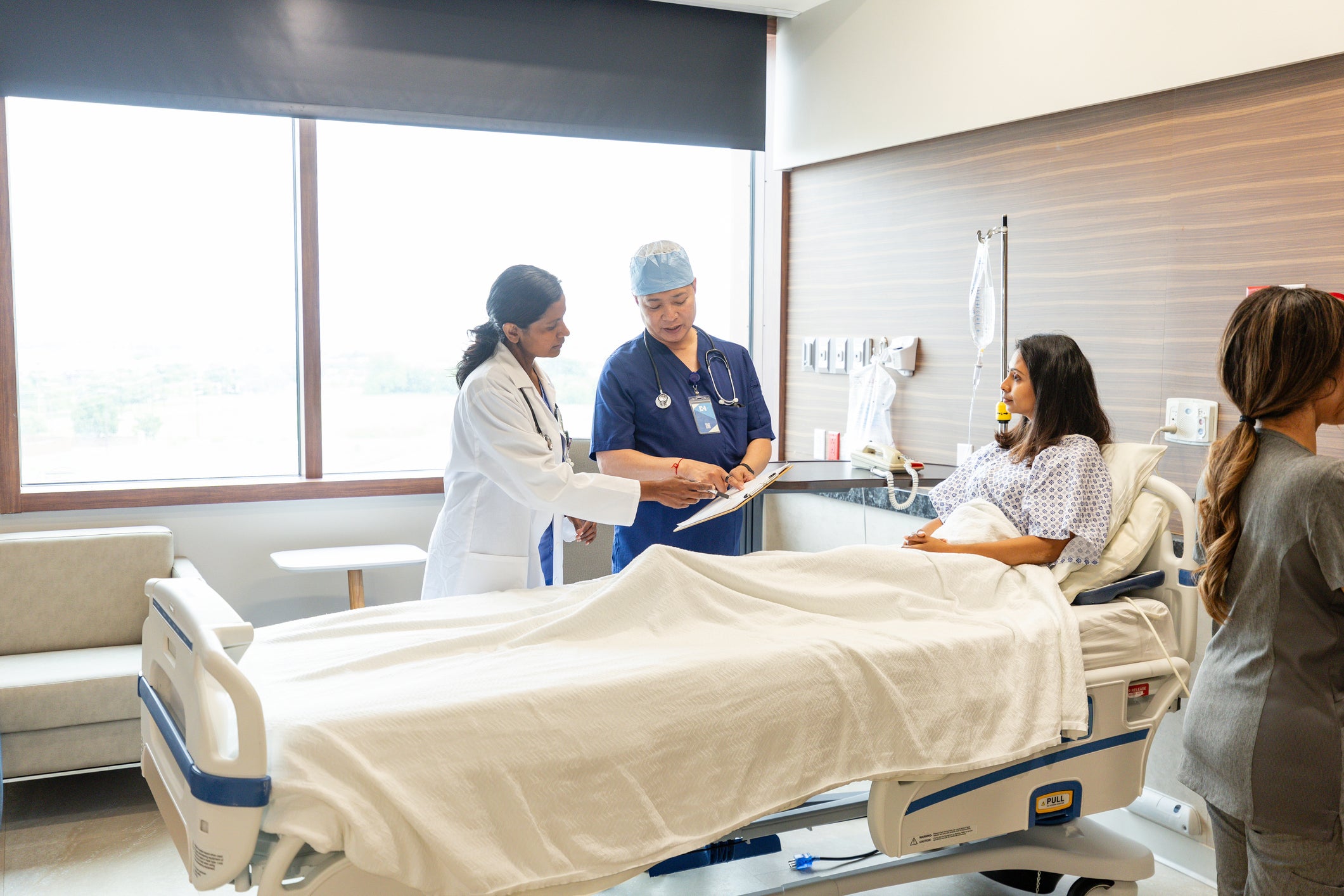Doctors confer while patient listens and nurse takes notes